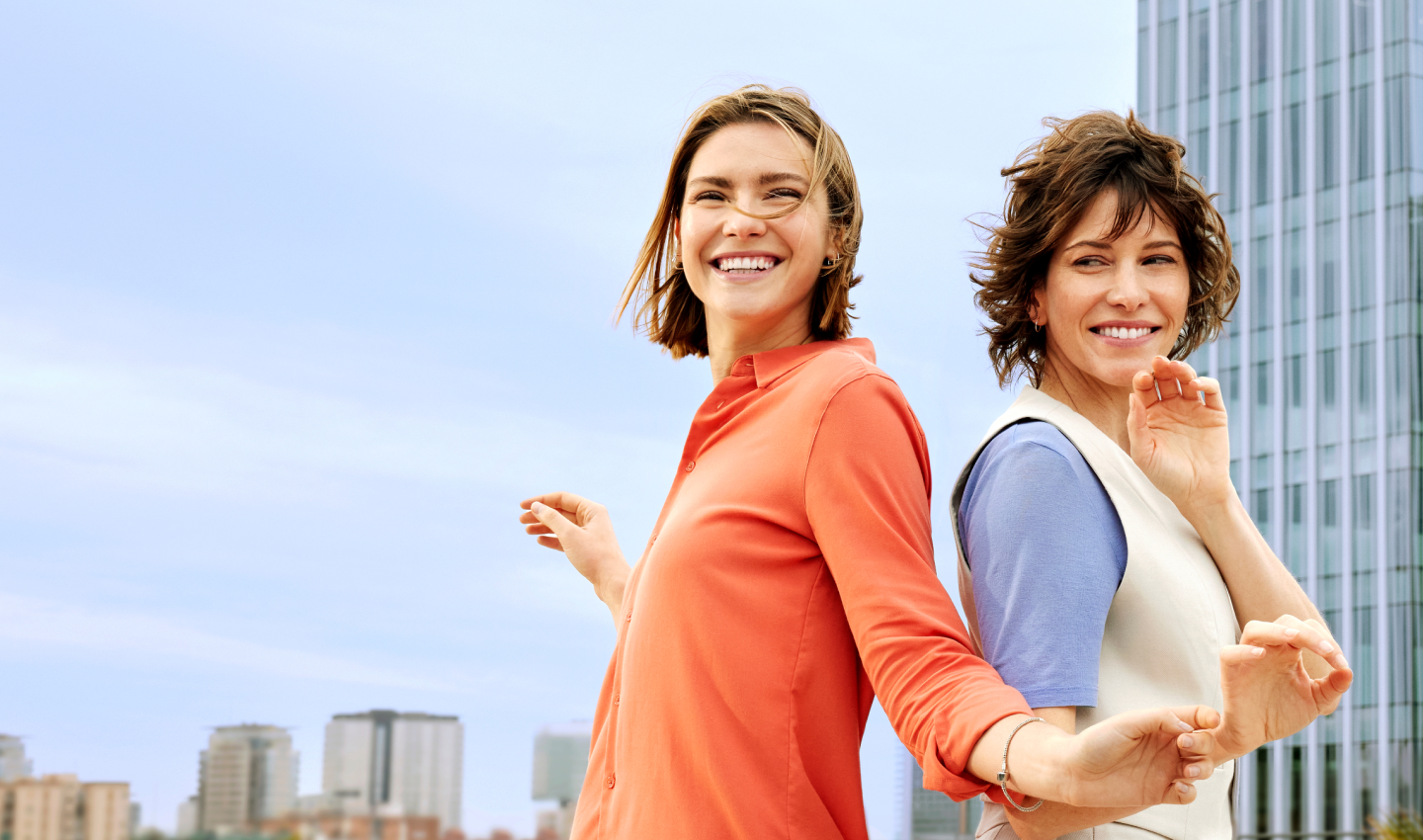 dos mujeres de espaldas entre ellas en la calle sonriendo